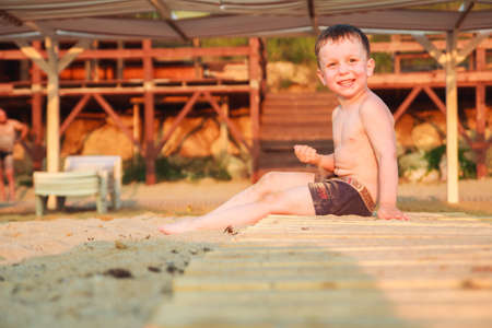 boy sitting on the beach at sunset.の写真素材