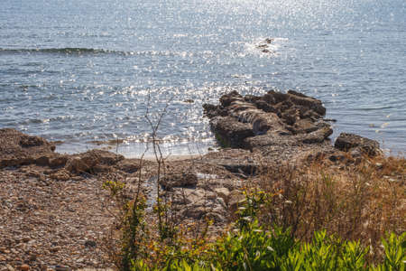 Blue water background with stones on the sandy shore. sea or ocean landscapeの写真素材