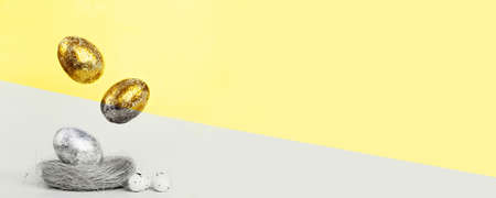 Illuminating Gold and silver Easter eggs levitation to the nest on a Ultimate Grey and yellow background. Easter conceptの写真素材