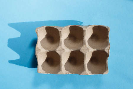 Empty eggs carton box with hard shadows on blue background.の写真素材