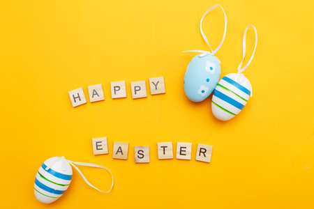 inscription happy easter with colorful handmade painted blue eggs on orange background
