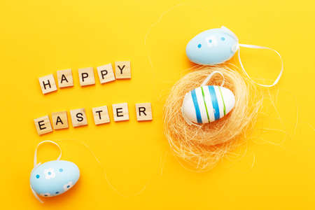 colorful handmade painted eggs in the nest on orange backgroundの写真素材