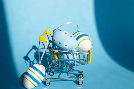 Easter eggs in the shopping cart on a blue backgroundの写真素材