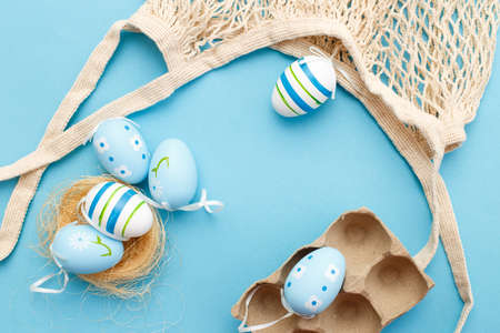 colorful easter painted eggs and cotton string bag on blue backgroundの写真素材