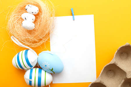 easter colorful eggs on orange background with sheet of paper for your textの写真素材