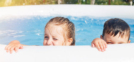portrait of happy boy and girl in the pool in the garden at summer.の写真素材