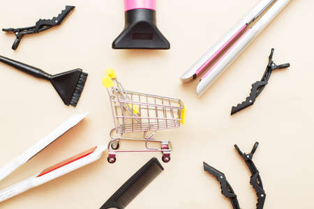 various hairdressing tools with shopping cart on a beige background. beauty salon concept.の写真素材