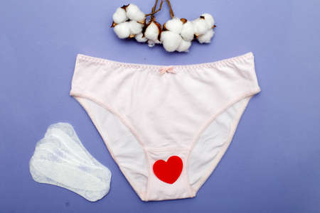 pink women's briefs with flower cotton and panty liners on a purple background. hygiene and women's health care concept.の写真素材
