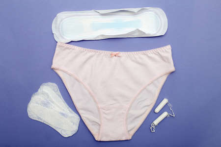 pink women's briefs tampons, pads and panty liners on a purple background. hygiene and women's health care concept.の写真素材