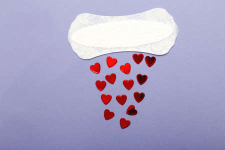 Women's daily hygiene pad on a purple background with red hearts.の写真素材