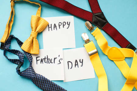 multicolored men's ties, suspenders and bow ties on blue background with copy space for your text....