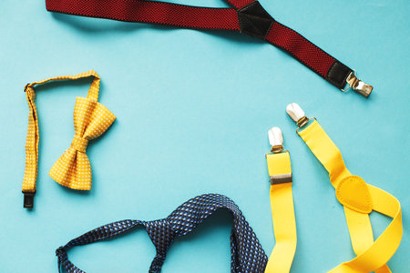 multicolored men's ties, suspenders and bow ties on blue background with copy space for your text. father's day concept.の写真素材