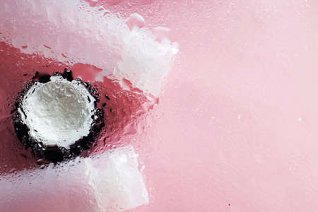 Concept of natural moisturizing skin care products. Face and hand cream under a glass surface with water on a pink background.の写真素材