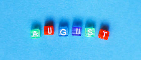 inscription August made by multicolor plastic cubes on a blue background. bannerの写真素材