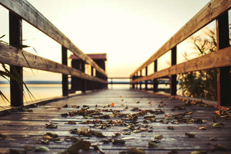 sunset on a wooden pier. Autumn landscape with falling leaves.の写真素材