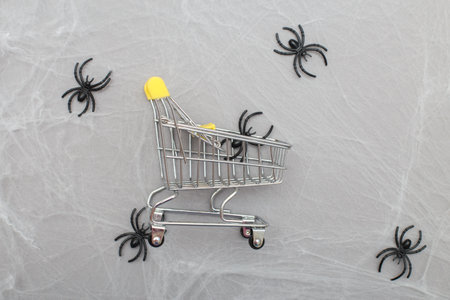 shopping cart with spider web and spiders on a gray background. Halloween shopping conceptの写真素材