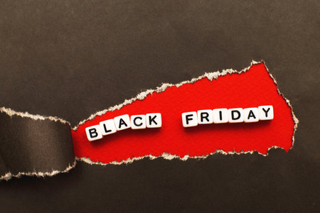 curl of torn black paper on red background. black friday sale conceptの写真素材