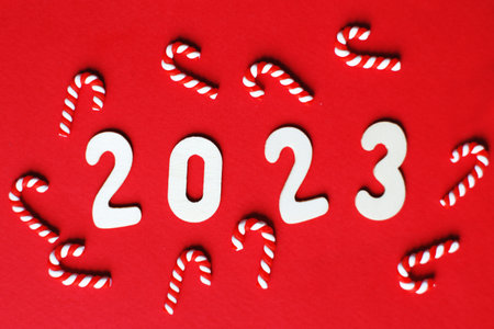 Flat lay Christmas composition with frame of candy canes and number 2023 on a red background. Copy space for text.の写真素材