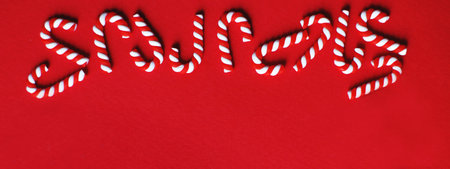 Flat lay Christmas composition with frame of candy canes on a red background. Copy space for text. bannerの写真素材