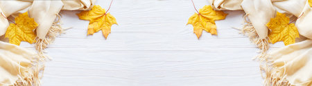 autumn leaves with a scarf on a wooden background with copy space. banner.の写真素材