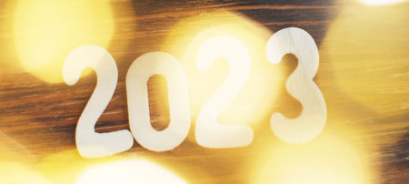wooden number 2023 on christmas beautifull shiny gold background. sparkle festive blurred bokeh.