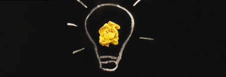 crumpled yelllow paper lightbulb as a concept creative idea and innovation on a blackboard background. bannerの写真素材