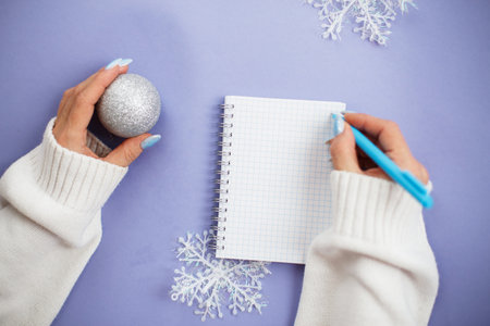 Woman hand with winter nails holding pen on notebook and writing wish list.の写真素材
