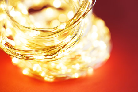christmas beautifull shiny gold garland on a red background. sparkle festive blurred background with...