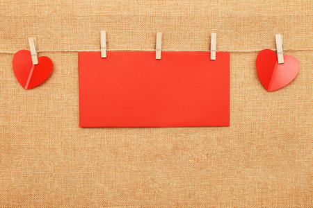 red hearts with paper note for text on clothes pin on brown textile background.の写真素材