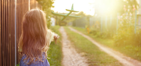 Happy child girl with long blond hair playing with toy airplane outdoor.の写真素材
