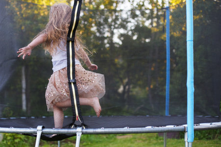a Little child girl jumping on the trampoline in the back yardの写真素材
