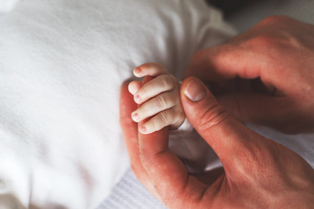Close up photo of father holding baby hand. New family, care, love and baby protection concept.