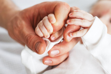 Close up photo of father holding baby hand. New family, care, love and baby protection concept.