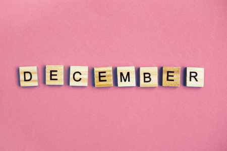 inscription December made by wooden cubes on a pastel pink backgroundの写真素材