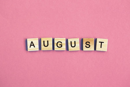 inscription August made by wooden cubes on a pastel pink backgroundの写真素材