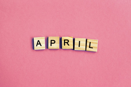 inscription April made by wooden cubes on a pastel pink backgroundの写真素材