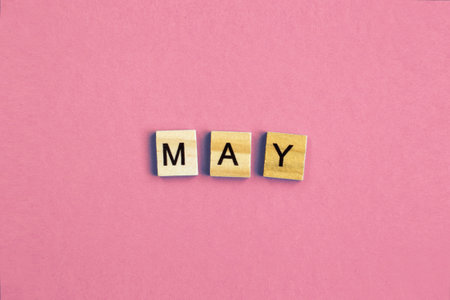 inscription May made by wooden cubes on a pastel pink backgroundの写真素材