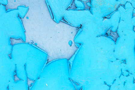 Old blue turquoise paint peeling from concrete or metal wall background. Texture of an old grunge plate with cracked paint with a hole.の写真素材