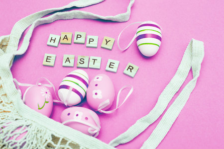 Happy easter with colorful painted eggs and cotton string bag on pink backgroundの写真素材