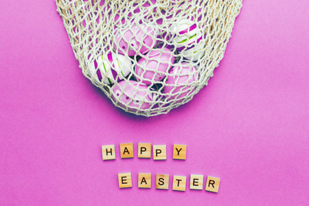 Happy easter with colorful painted eggs and cotton string bag on pink backgroundの写真素材