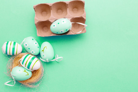 colorful handmade painted eggs in the nest and cardboard box on green backgroundの写真素材