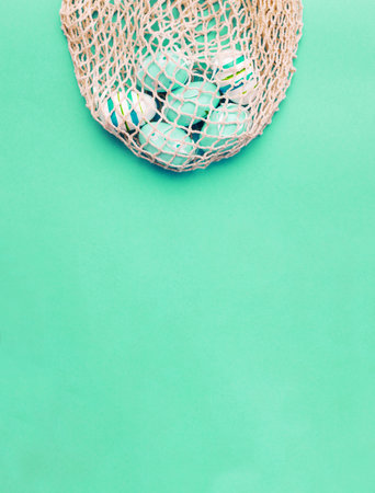 easter colorful painted eggs in the cotton string bag on green background. bannerの写真素材