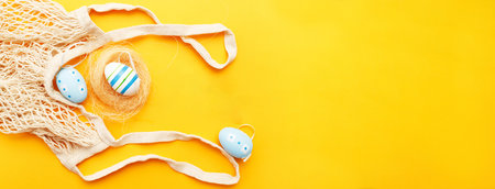 happy easter with colorful painted eggs and cotton string bag on orange backgroundの写真素材