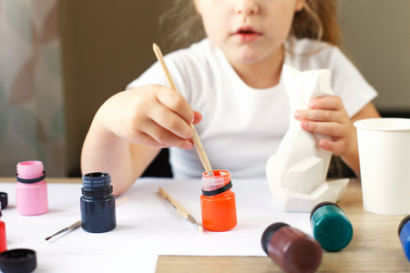 a little girl paints a toy fox made of clay. DIY conceptの写真素材