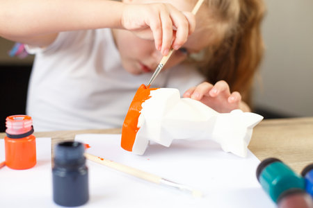 a little girl paints a toy fox made of clay. DIY conceptの写真素材