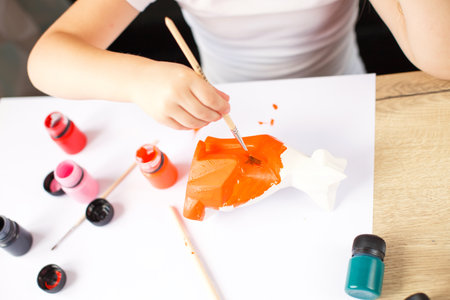 a little girl paints a toy fox made of clay. DIY conceptの写真素材