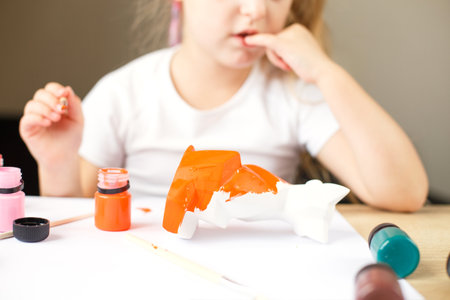 a little girl paints a toy fox made of clay. DIY conceptの写真素材
