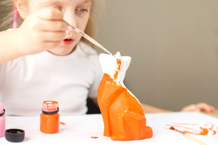 a little girl paints a toy fox made of clay. DIY conceptの写真素材