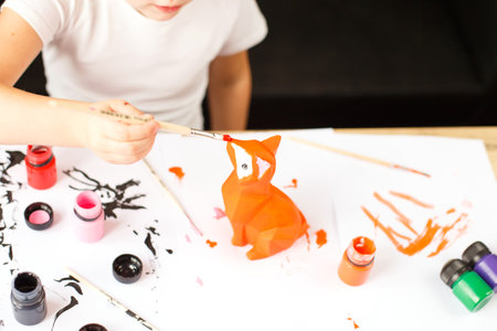 a little girl paints a toy fox made of clay. DIY conceptの写真素材