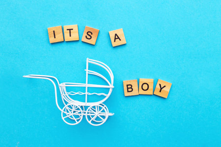 Its a boy. Little vintage white baby carriage stroller or pram on a blue background. Symbol of childbirth, parenthood, birth concept. Invitation festive greeting card on child birthday party.の写真素材